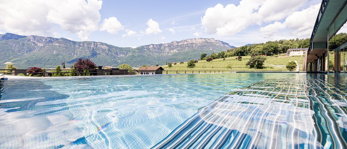Urlaub in Südtirol im Hotel mit Pool am See Infinity-Pool mit Bergblick bei sonnigem Wetter