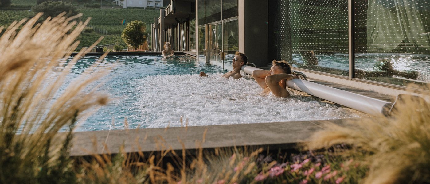 Hotel ad Appiano sulla Strada del Vino: il Gartenhotel Moser Persone si rilassano in una piscina all'aperto accanto a un edificio moderno in campagna
