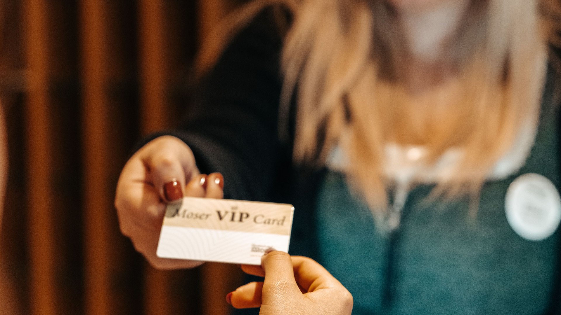 Hotel a Bolzano e dintorni: VIP Card Donna consegna una carta VIP a un'altra persona alla reception
