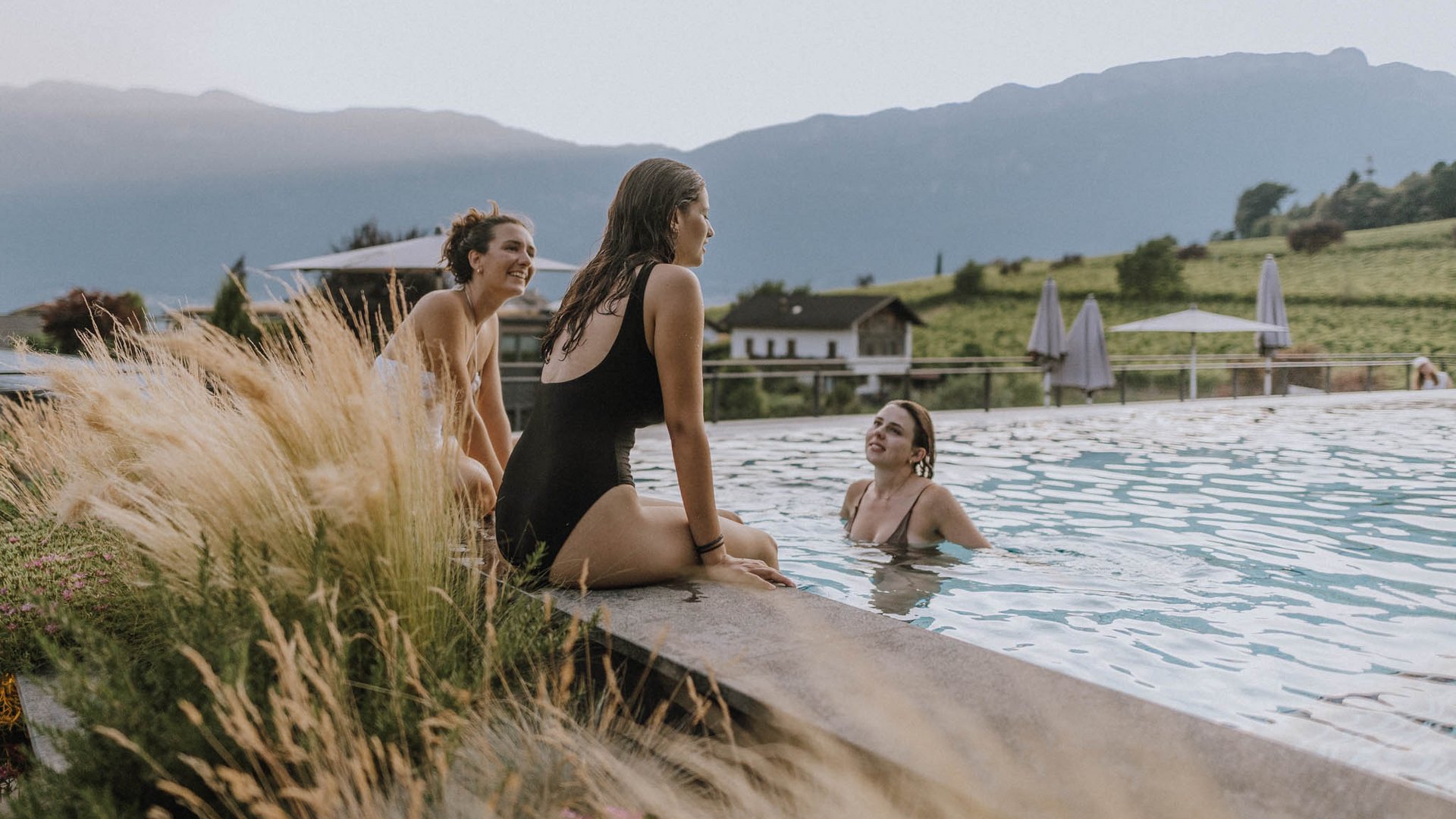 Hotel am Montiggler See: Gartenhotel Moser Drei Frauen entspannen am Pool mit Bergen im Hintergrund