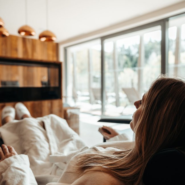 Day spa in South Tyrol: Gartenhotel Moser Woman relaxing in white bathrobe on lounge chair in bright room