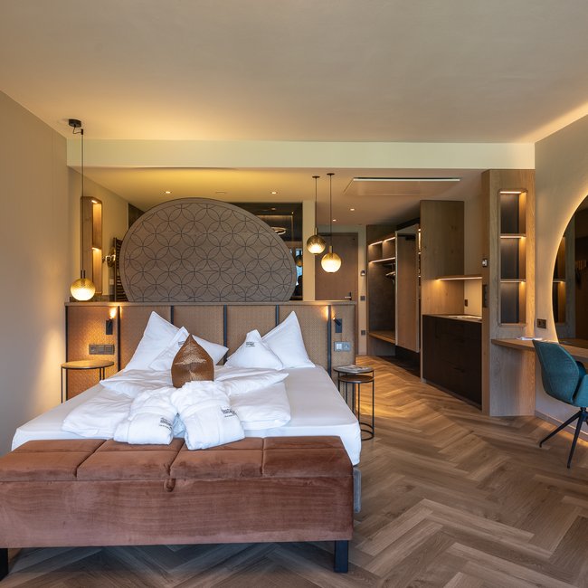 Neu ab 2024 im Gartenhotel Moser Modern eingerichtetes Hotelzimmer mit Doppelbett, Sitzbank und großem Spiegel