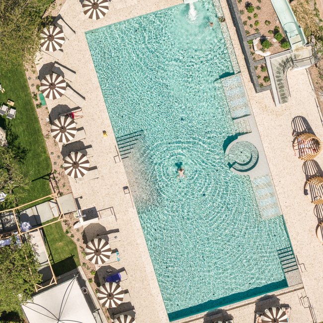 Neu ab 2026 im Gartenhotel Moser Blick von oben auf einen Pool mit Wasserrutsche und Sonnenliegen