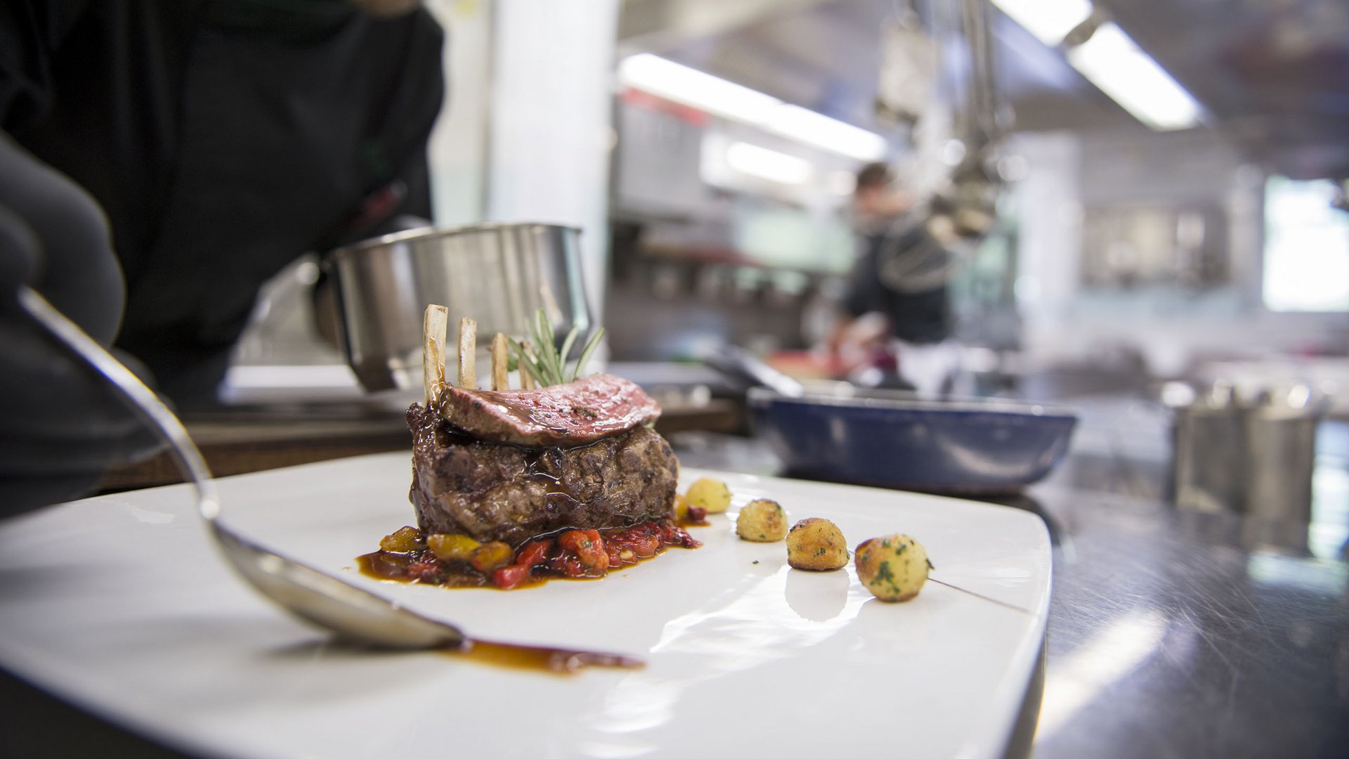 Hotel near Eppan an der Weinstraße: Gartenhotel Moser Chef plating fine meat dish in professional kitchen