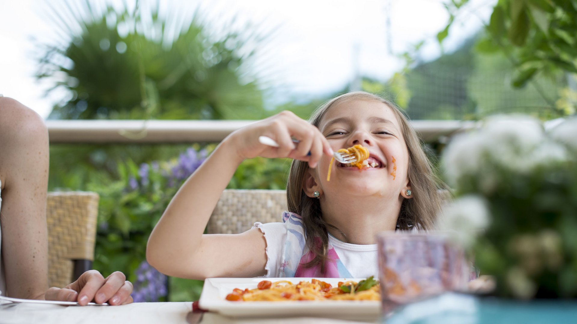 Family hotels in South Tyrol with 4-star-superior service Girl laughing while eating spaghetti outdoors