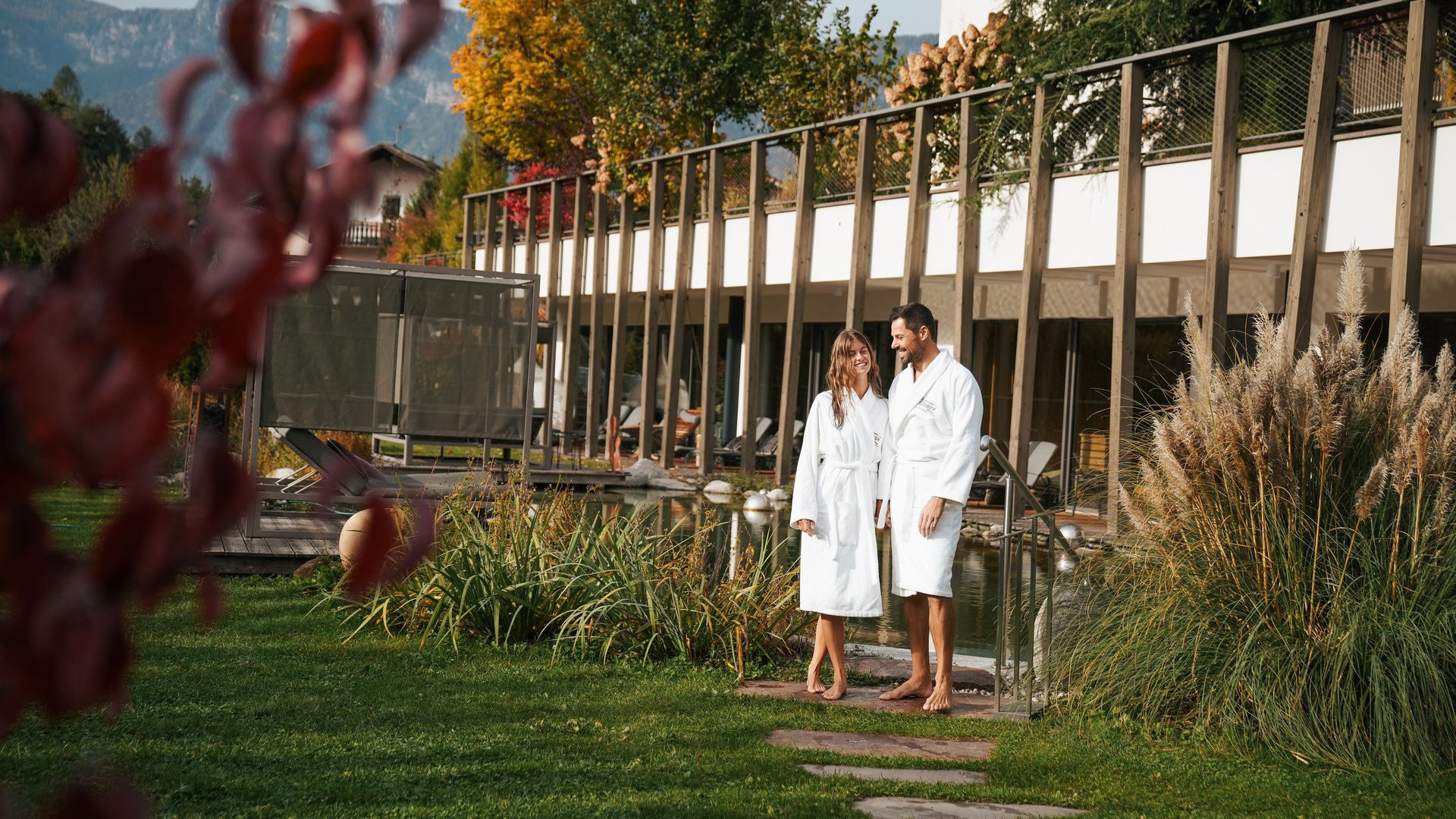Wellnesshotel mit Whirlpool und Saunawelt Paar in weißen Bademänteln im Garten eines Wellnesshotels im Herbst