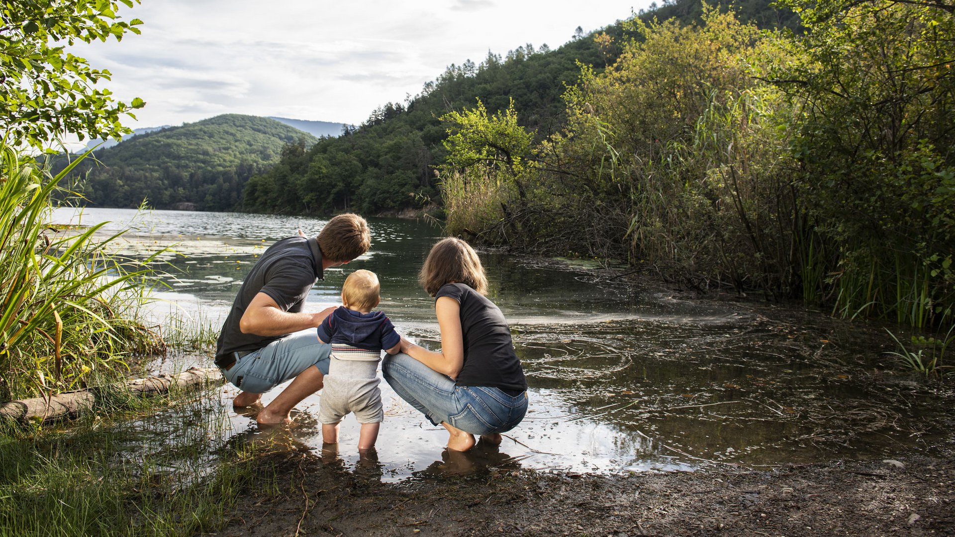 Kinderhotel am See: Gartenhotel Moser Eltern mit Baby am Waldrand spielen im flachen Seeuferwasser
