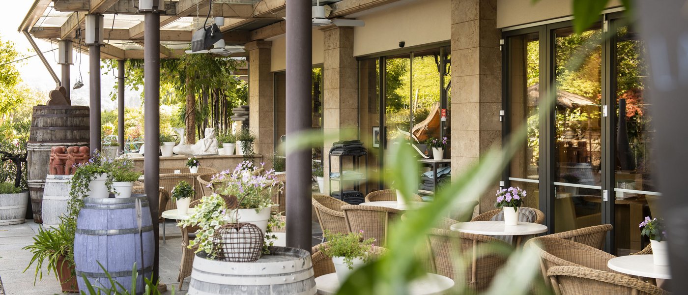 Wellness hotel with gourmet cuisine: Gartenhotel Moser Cozy outdoor terrace with barrel tables and plants at a café