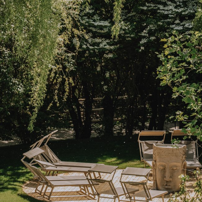 Neu ab 2026 im Gartenhotel Moser Liegestühle auf Rasenfläche unter Baumzweigen im Park