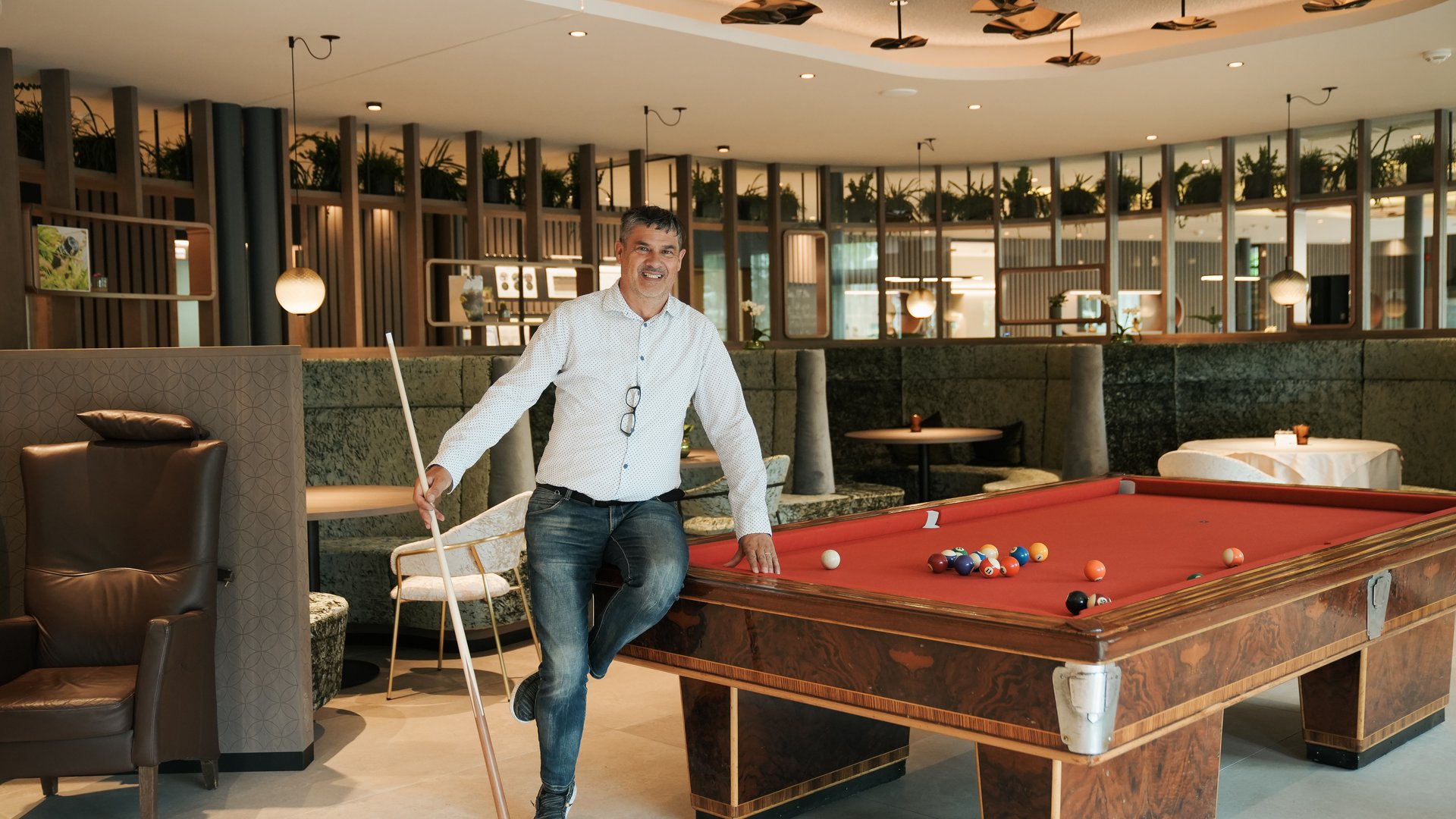 Novità a partire dal 2024 al Gartenhotel Moser Uomo che sorride appoggiato al tavolo da biliardo in ambiente moderno