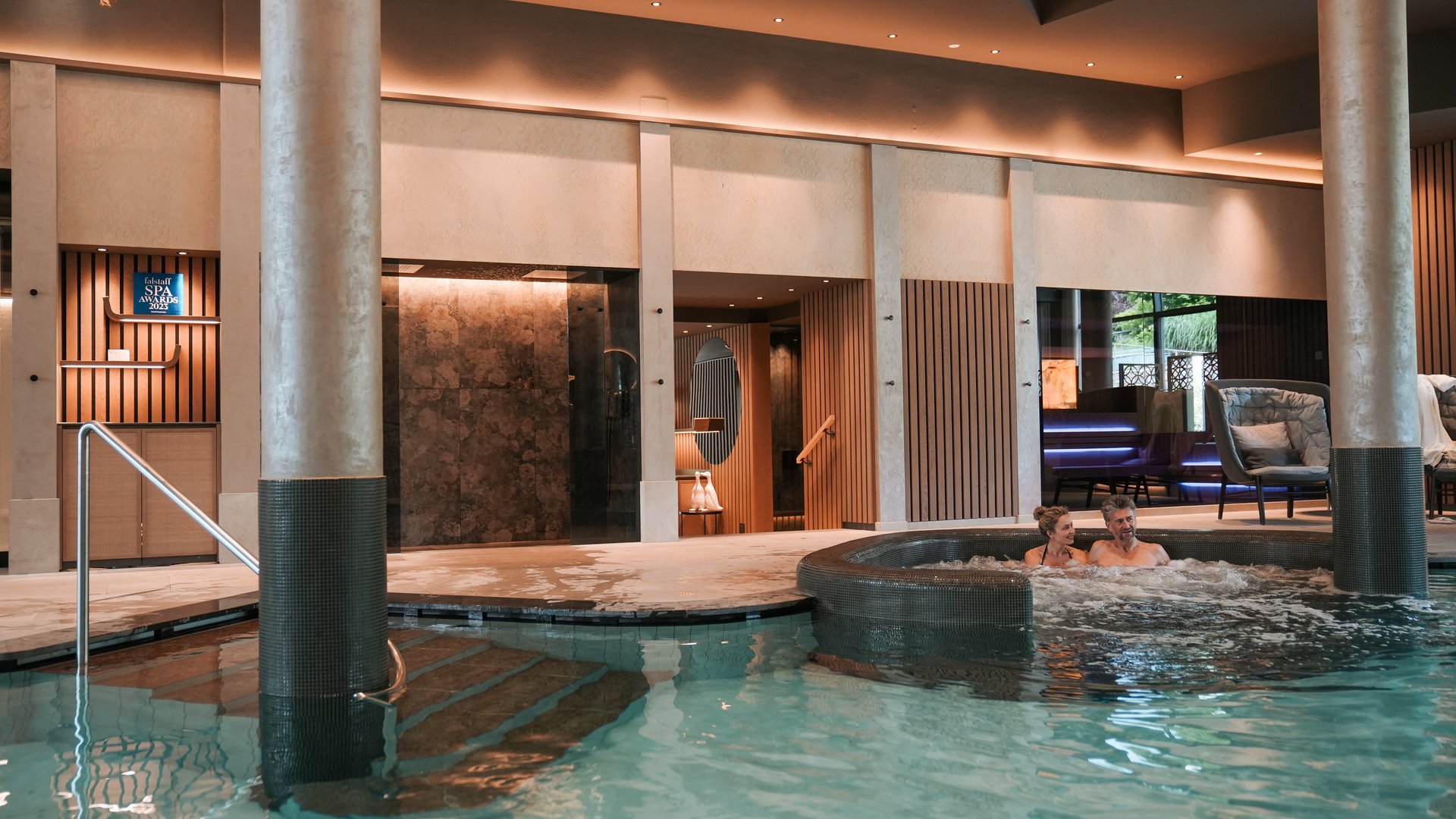 Day spa in South Tyrol: Gartenhotel Moser Couple relaxing in hot tub inside modern spa with pool