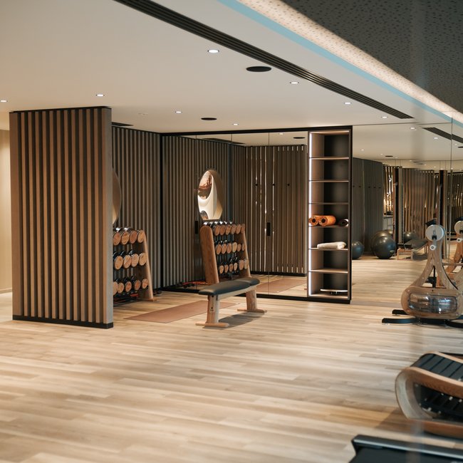 Sporthotels in Südtirol: Gartenhotel Moser Moderner Fitnessraum mit Hanteln, Sitzbank und Holzboden