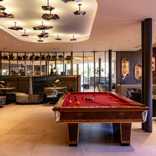 Neu ab 2024 im Gartenhotel Moser Moderner Lounge-Bereich mit Billardtisch und Sitzgelegenheiten bei Tageslicht