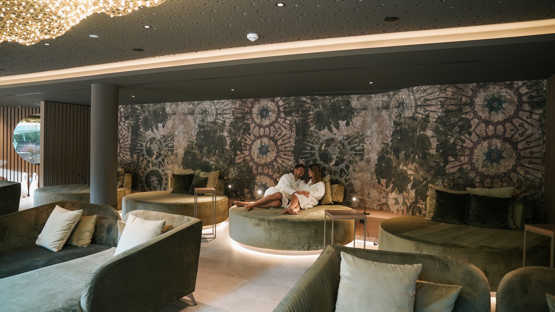 Hotels near Lago di Caldaro with 4-star superior service Couple relaxing in luxury spa lounge with round seating and dim ambient lighting