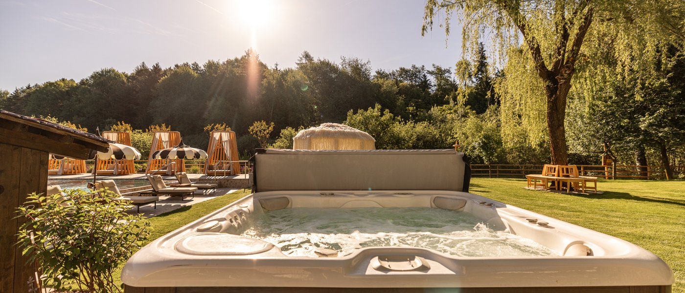 Hotel in Alto Adige con piscina Vasca idromassaggio all'aperto con lettini e alberi al sole