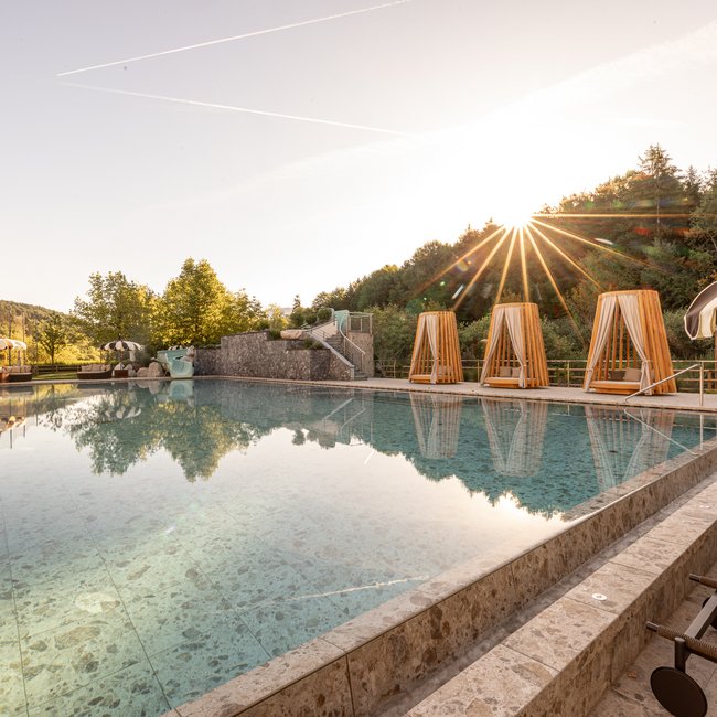 Hotel in Alto Adige con piscina Piscina all'aperto con lettini e ombrelloni al tramonto