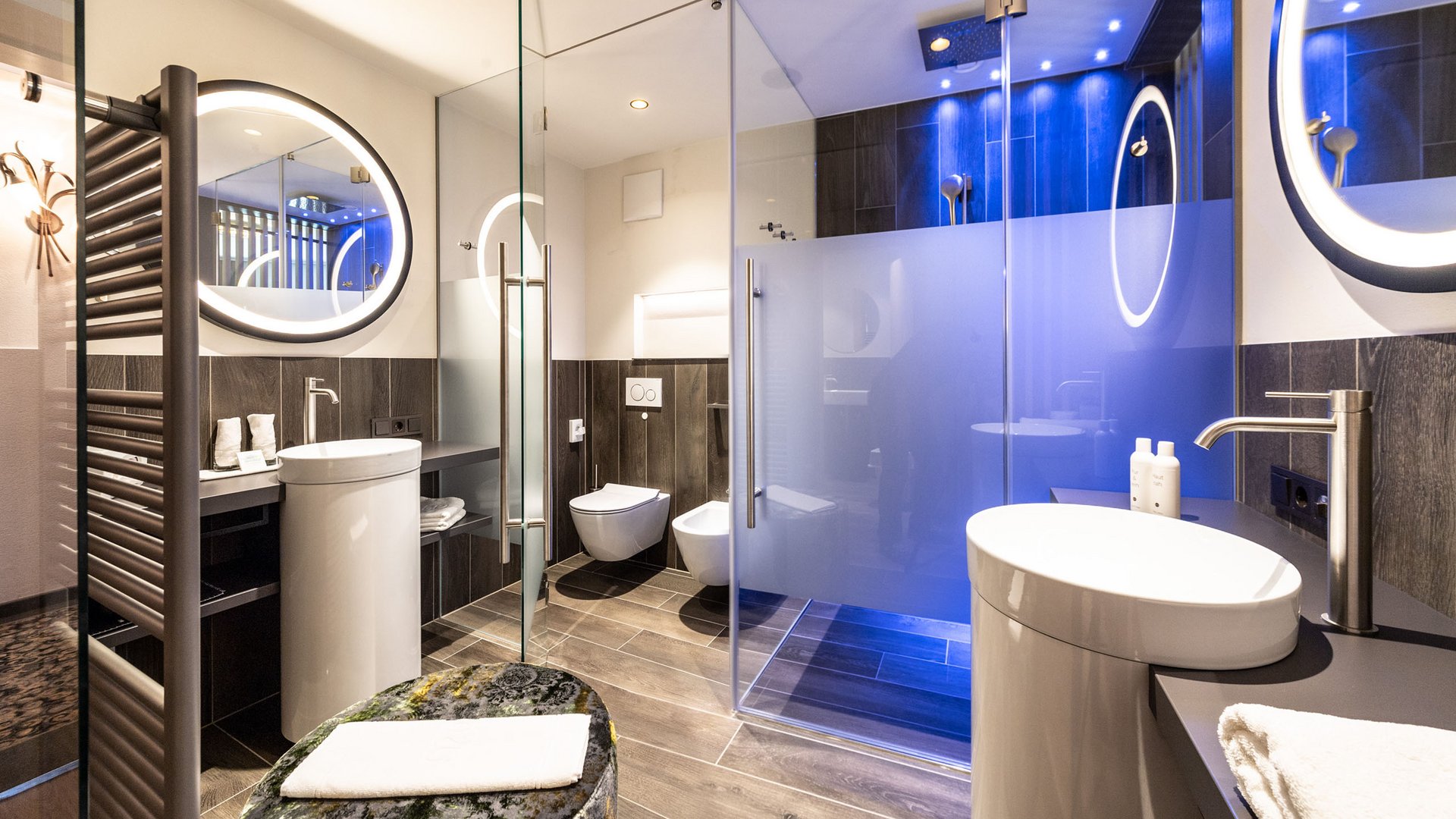 Hotel an der Weinstraße in Südtirol Modernes Badezimmer mit Glasdusche, zwei Waschbecken und beleuchtetem Spiegel