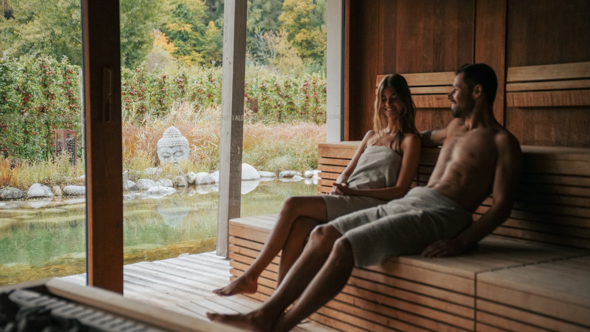 Hotels near Lago di Caldaro with 4-star superior service Couple relaxing in sauna with view of garden and Buddha statue