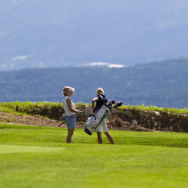 Sporthotel in Südtirol: Gartenhotel Moser Zwei Golferinnen auf dem Grün mit Fahne Nummer 9 und Bergkulisse