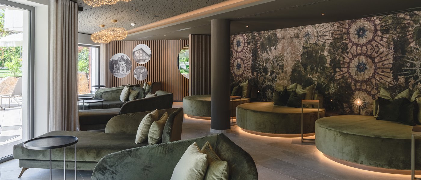 Urlaub in Südtirol im Hotel mit Pool am See Eleganter Lounge-Bereich mit grünen Sitzmöbeln und leuchtenden Deckenlampen
