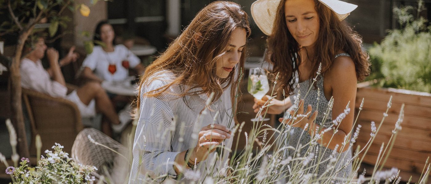 Hotel in Alto Adige con piscina Due donne osservano le piante in un giardino soleggiato