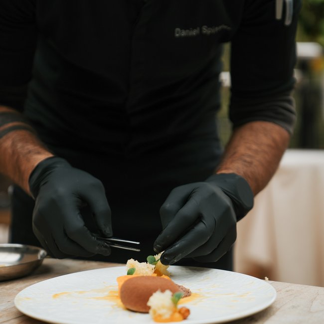 Im Wellnesshotel glutenfrei genießen Koch arrangiert feines Essen mit Pinzette auf einem Teller