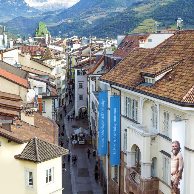 Hotels on Lago di Monticolo: South Tyrol awaits View of an alpine town street with museum signs and mountains in the background