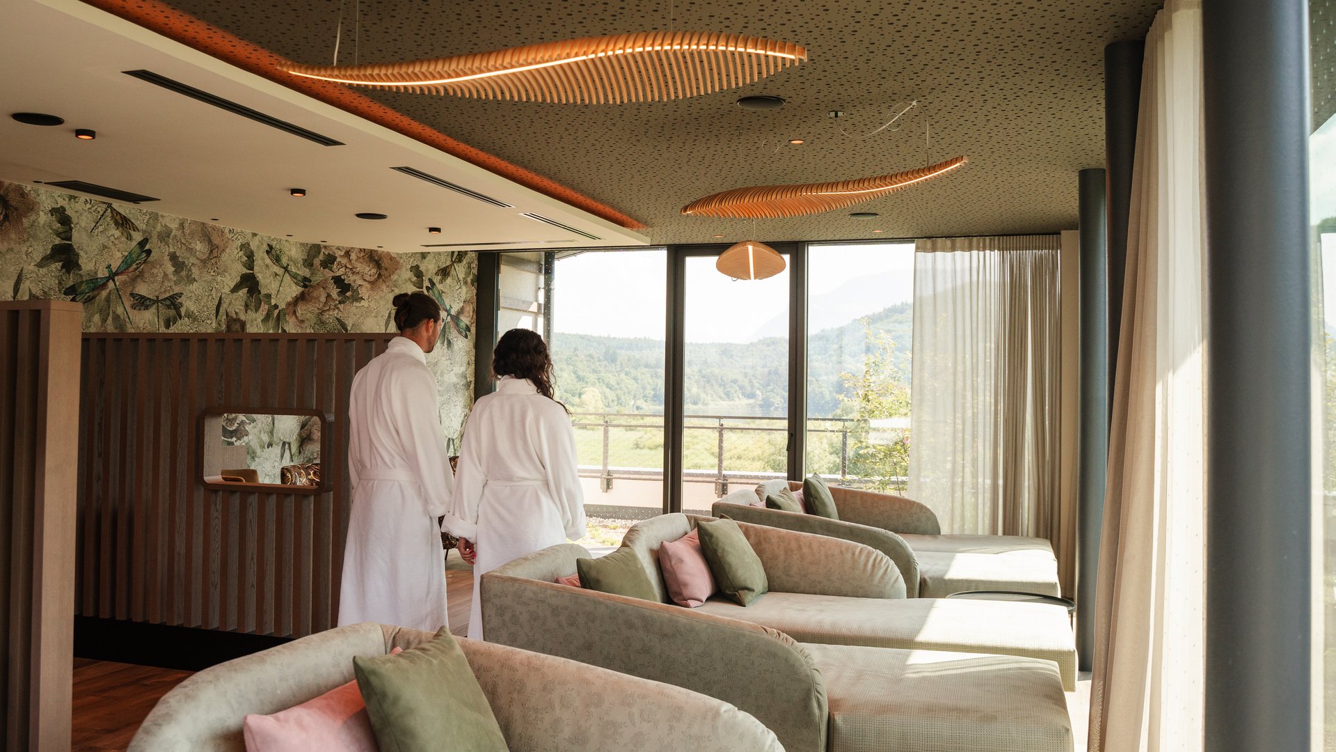 Day spa in South Tyrol: Gartenhotel Moser Couple in white robes looking at landscape through panoramic spa windows