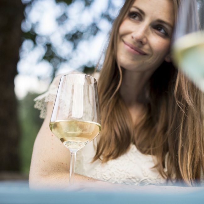 Hotel sulla Strada del Vino in Alto Adige: Gartenhotel Moser Donna sorride con bicchiere di vino bianco all'aperto