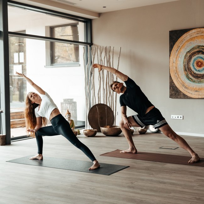 Yoga in Alto Adige Due persone fanno yoga in una stanza luminosa su tappetini da yoga