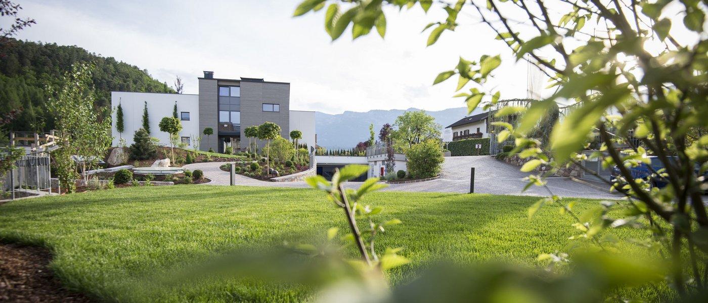 Laghi balneabili in Alto Adige: cosa c’è da sapere Case moderne con giardino curato e montagne sullo sfondo