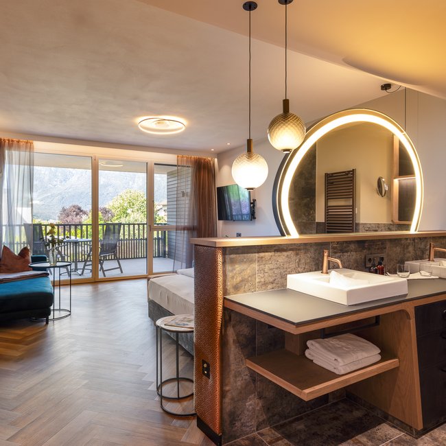 Neu ab 2024 im Gartenhotel Moser Modernes Hotelzimmer mit Balkon und beleuchtetem Badezimmerspiegel