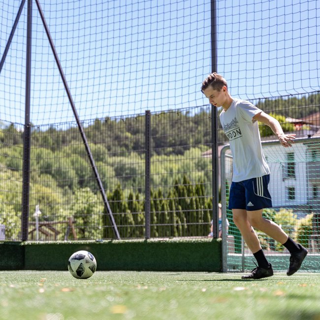 Family hotels in South Tyrol with 4-star-superior service Young man playing soccer on outdoor field with goal and net