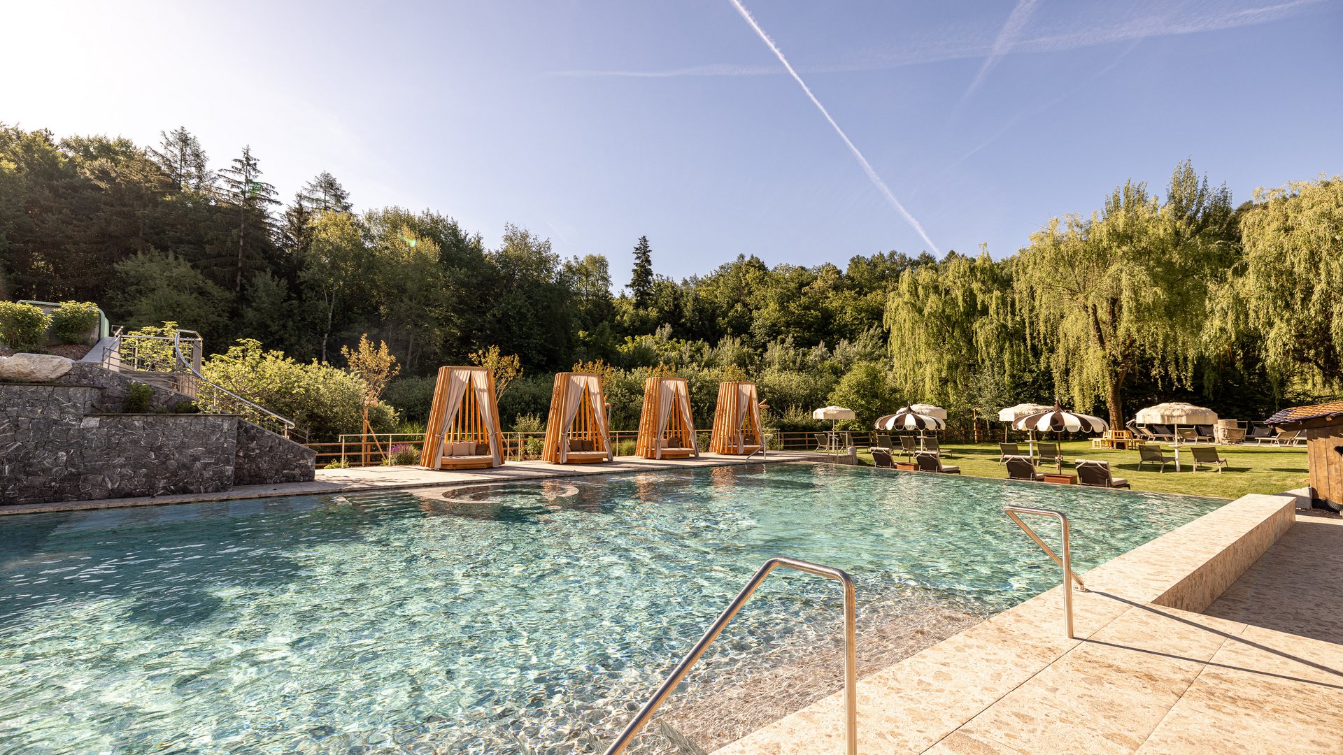 Novità a partire dal 2026 al Gartenhotel Moser Piscina all'aperto con lettini e ombrelloni davanti a una foresta