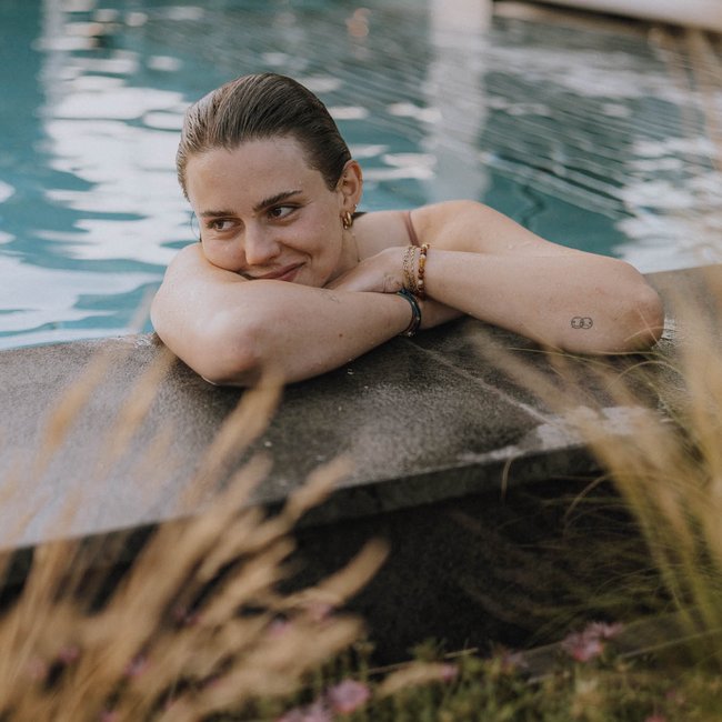 Hotel bei Eppan an der Weinstraße: Gartenhotel Moser Frau lehnt entspannt am Poolrand mit Blick auf eine Person im Vordergrund