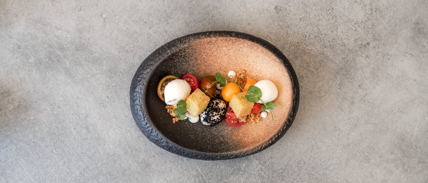 Wellnesshotel mit Gourmetküche: Gartenhotel Moser Kunstvoll angerichtete Vorspeise mit Tomaten, Käse und Brot auf einem Keramikteller