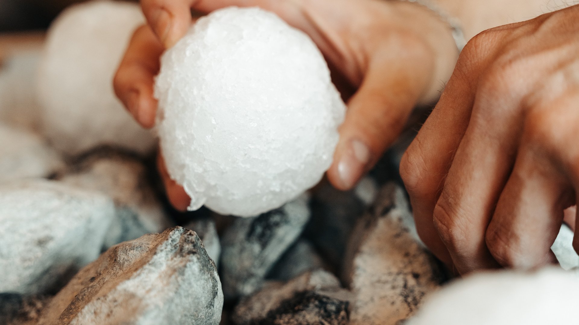 Wellnesshotel mit Whirlpool und Saunawelt Hände halten weißen Saunaaufgussstein auf heißen Steinen