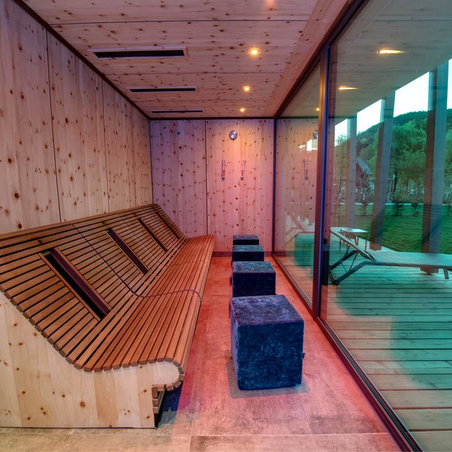 Day spa in South Tyrol: Gartenhotel Moser Wooden sauna with glass window overlooking outdoor area with lounge chair