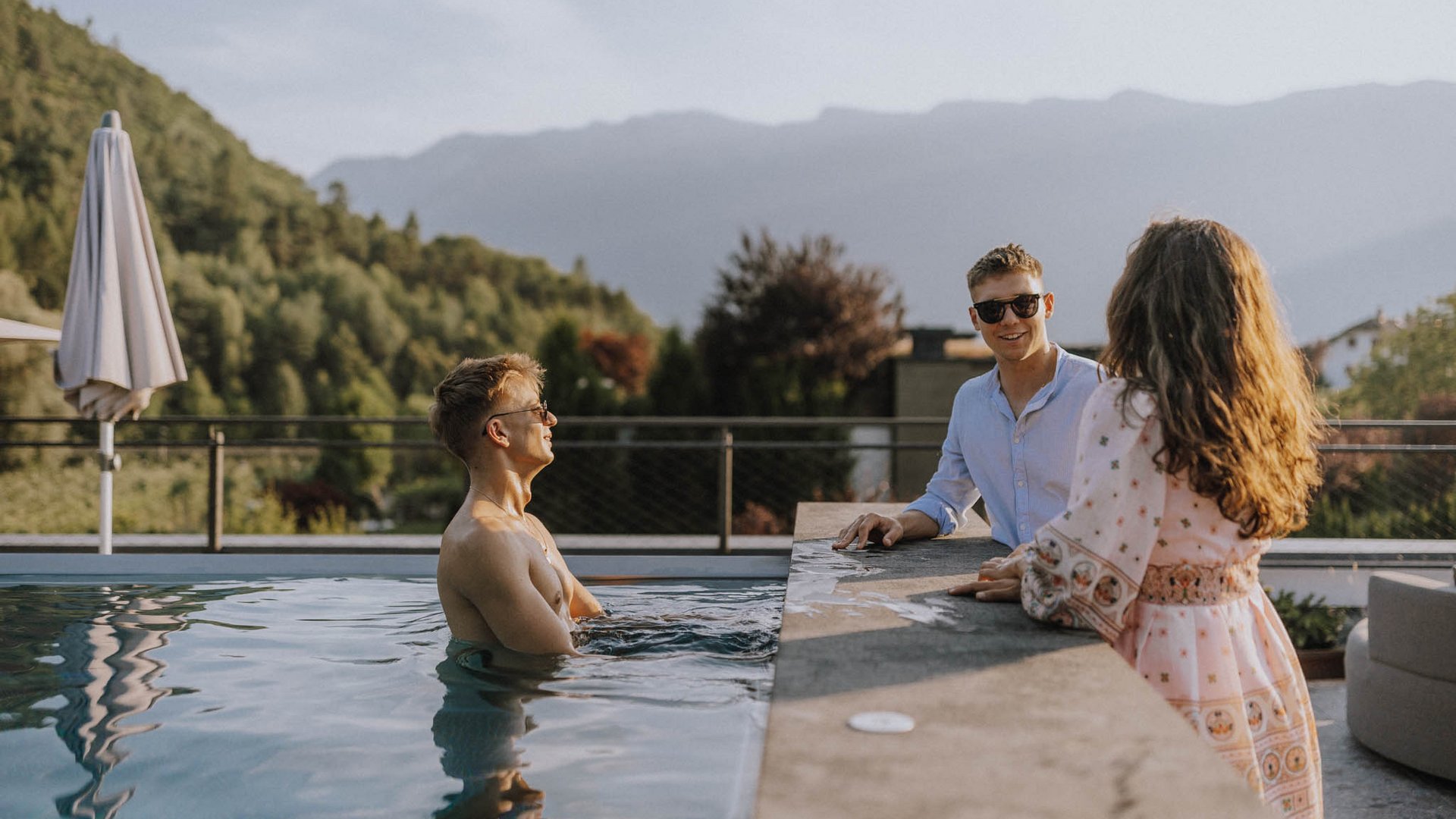 Laghi balneabili in Alto Adige: cosa c’è da sapere Persone che si godono il tempo rilassante in piscina con vista sulle montagne