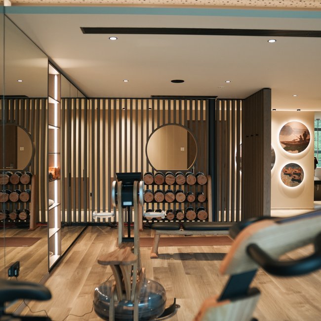 Sporthotels in Südtirol: Gartenhotel Moser Moderner Fitnessraum mit Hanteln, Rudergerät und Holzvertäfelung