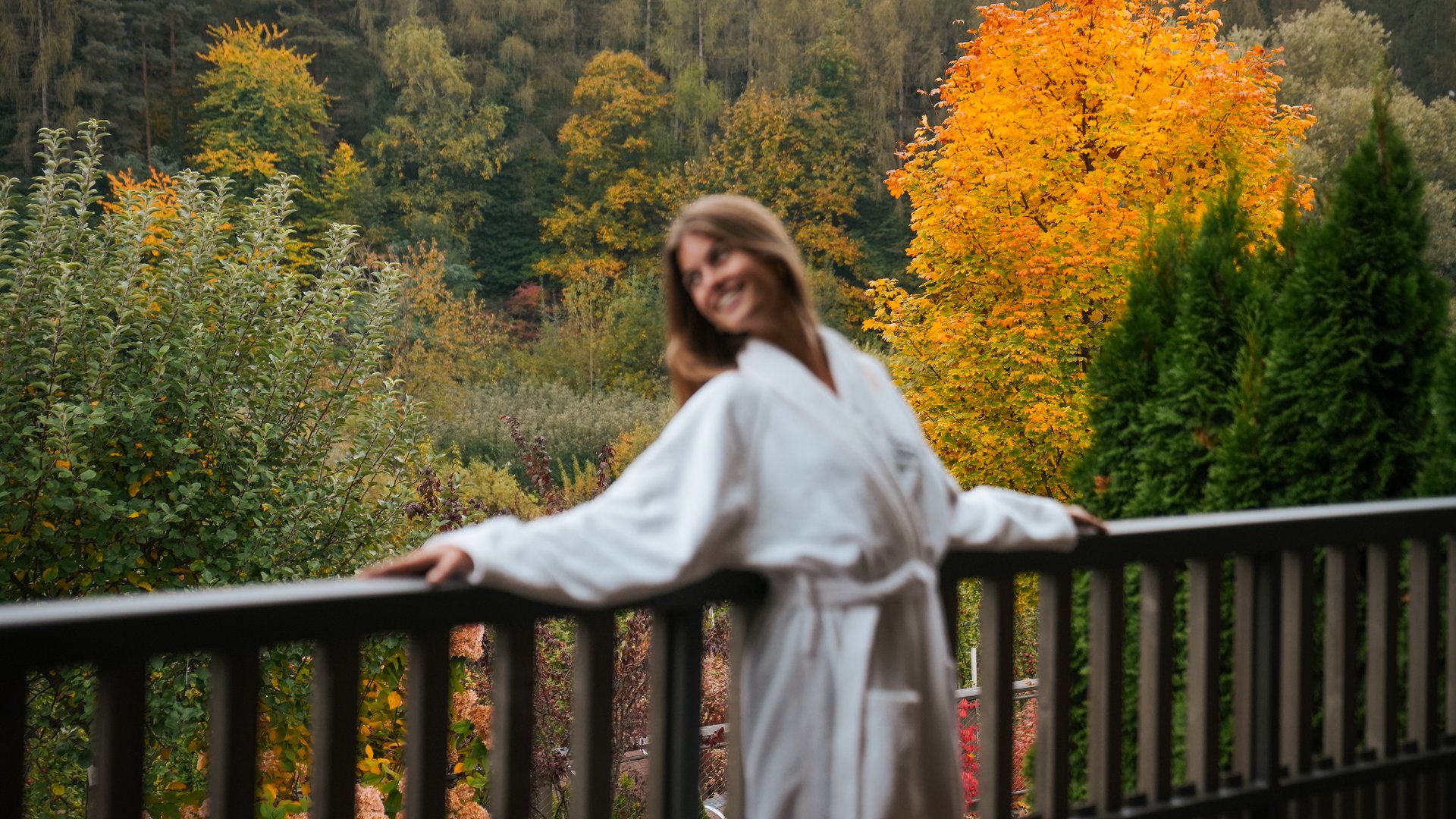 Hotels near Lago di Caldaro with 4-star superior service Woman in white robe on balcony with autumn colorful foliage