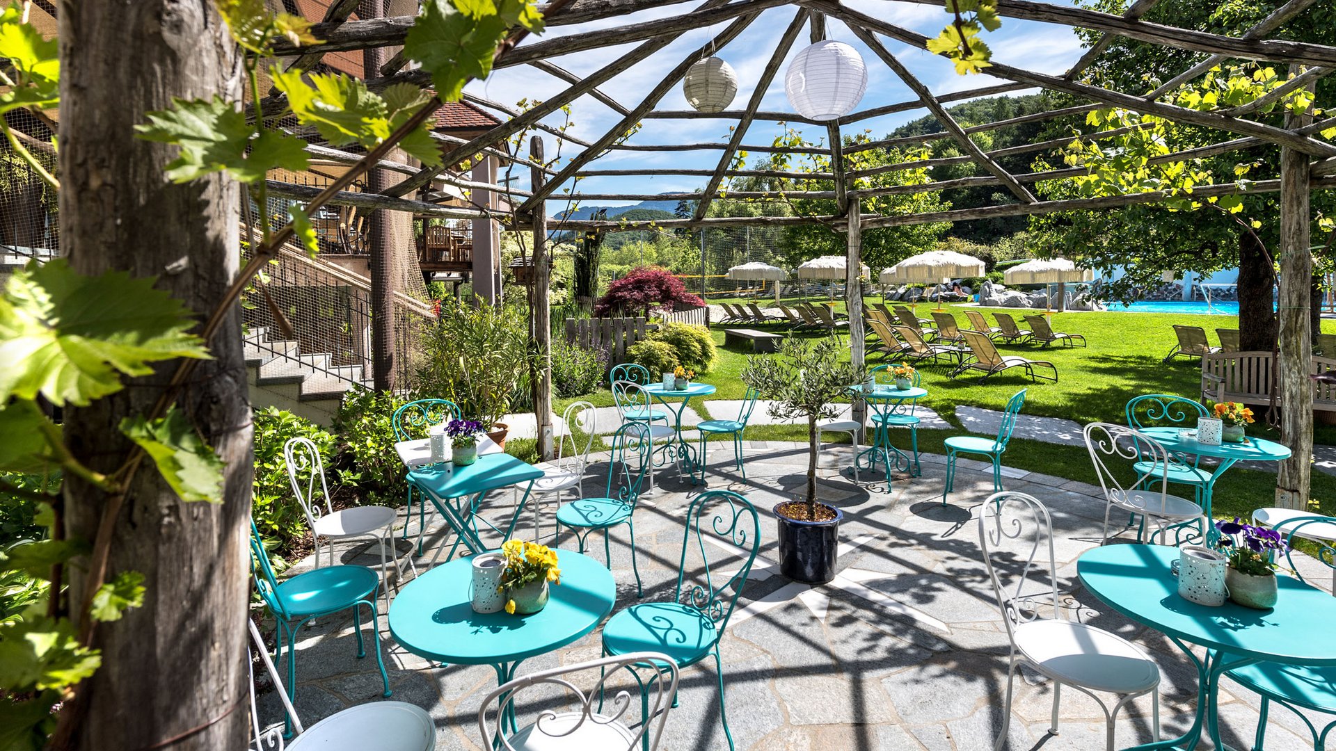 Un hotel senza glutine in Alto Adige: il Gartenhotel Moser Area esterna coperta con tavoli, sedie e vista su lettini nel giardino