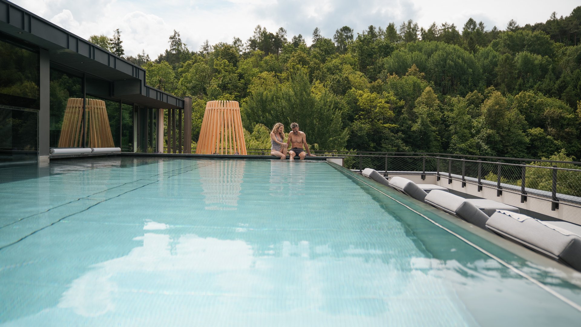 Day spa in South Tyrol: Gartenhotel Moser Couple sitting at the edge of a pool overlooking the forest