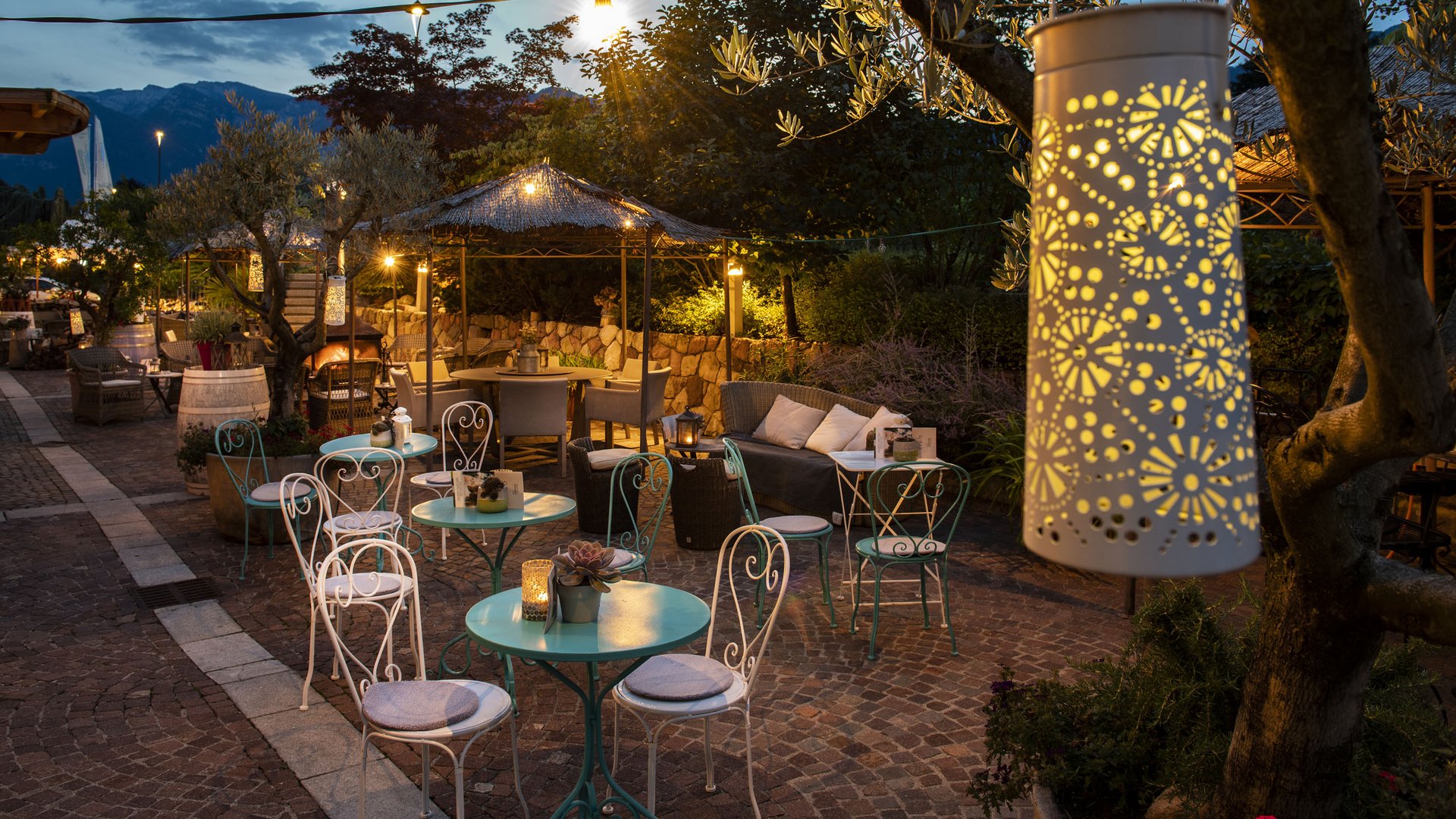 Un hotel senza glutine in Alto Adige: il Gartenhotel Moser Terrazza esterna serale con tavoli, sedie e illuminazione decorativa