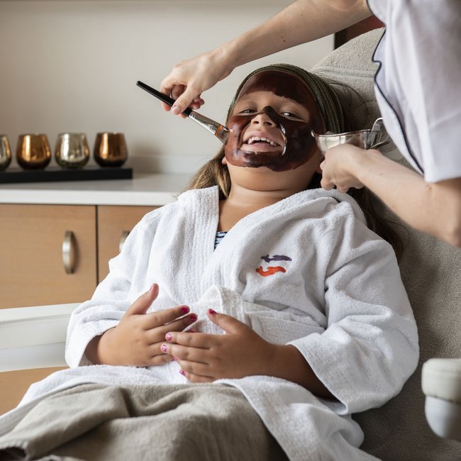 Hotel am Montiggler See: Gartenhotel Moser Kind bekommt Gesichtsmaske im Spa getragen von Fachkraft