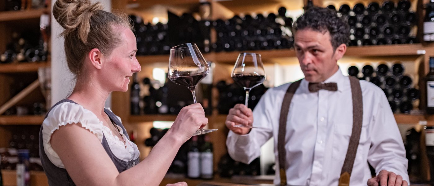 Hotel on the Wine Road in South Tyrol Woman and man clinking red wine glasses in a wine cellar bar
