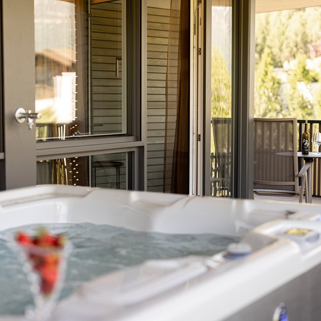 Neu ab 2024 im Gartenhotel Moser Whirlpool auf einer Terrasse mit Tisch und Stuhl im Hintergrund