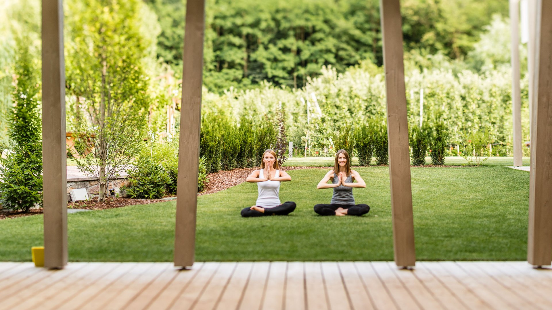 Hotel am Montiggler See: Gartenhotel Moser Zwei Frauen praktizieren Yoga im Garten auf der Wiese